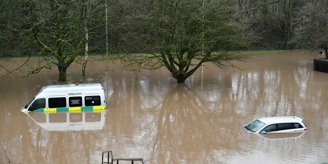 An ambulance, left, and a vehicle are submerged after flooding in Nantgarw, Wales, Sunday, Feb. 16, 2020.