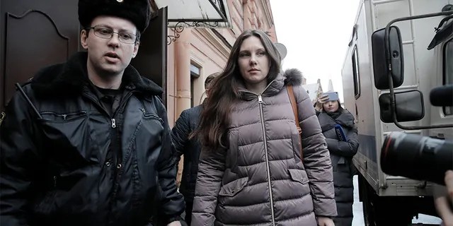 Alla Ilyina, who broke out of the hospital on Feb. 7 after learning that she would have to spend 14 days in isolation instead of the 24 hours doctors promised her, is escorted by a bailiff from a court after a session in St. Petersburg, Russia, on Monday.