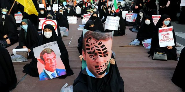 Iranian protesters hold defaced pictures of French President Emmanuel Macron during a protest against Macron and the publishing of caricatures of the Prophet Muhammad they deem blasphemous, in front of French Embassy in Tehran, Iran, Wednesday, Oct. 28, 2020. (AP Photo/Ebrahim Noroozi)