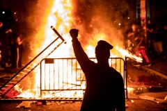 An individual raises a fist near a fire during a riot outside the White House after the death of George Floyd. (Photo credit: SAMUEL CORUM/AFP via Getty Images)