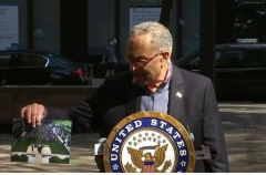 Two masked pedestrians look over at unmasked Sen. Chuck Schumer as he stands on a New York City sidewalk and displays a photo of the White House ceremony announcing the Supreme Court nomation of Amy Coney Barrett. (Screen Capture)